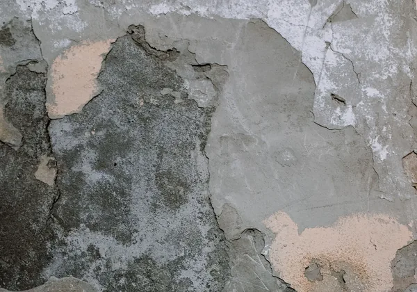 Muro con el revestimiento desprendido y cemento gris expuesto con manchas oscuras