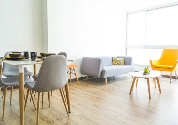 Sala de estar y comedor amoblados de un departamento, con ventanales y piso flotante